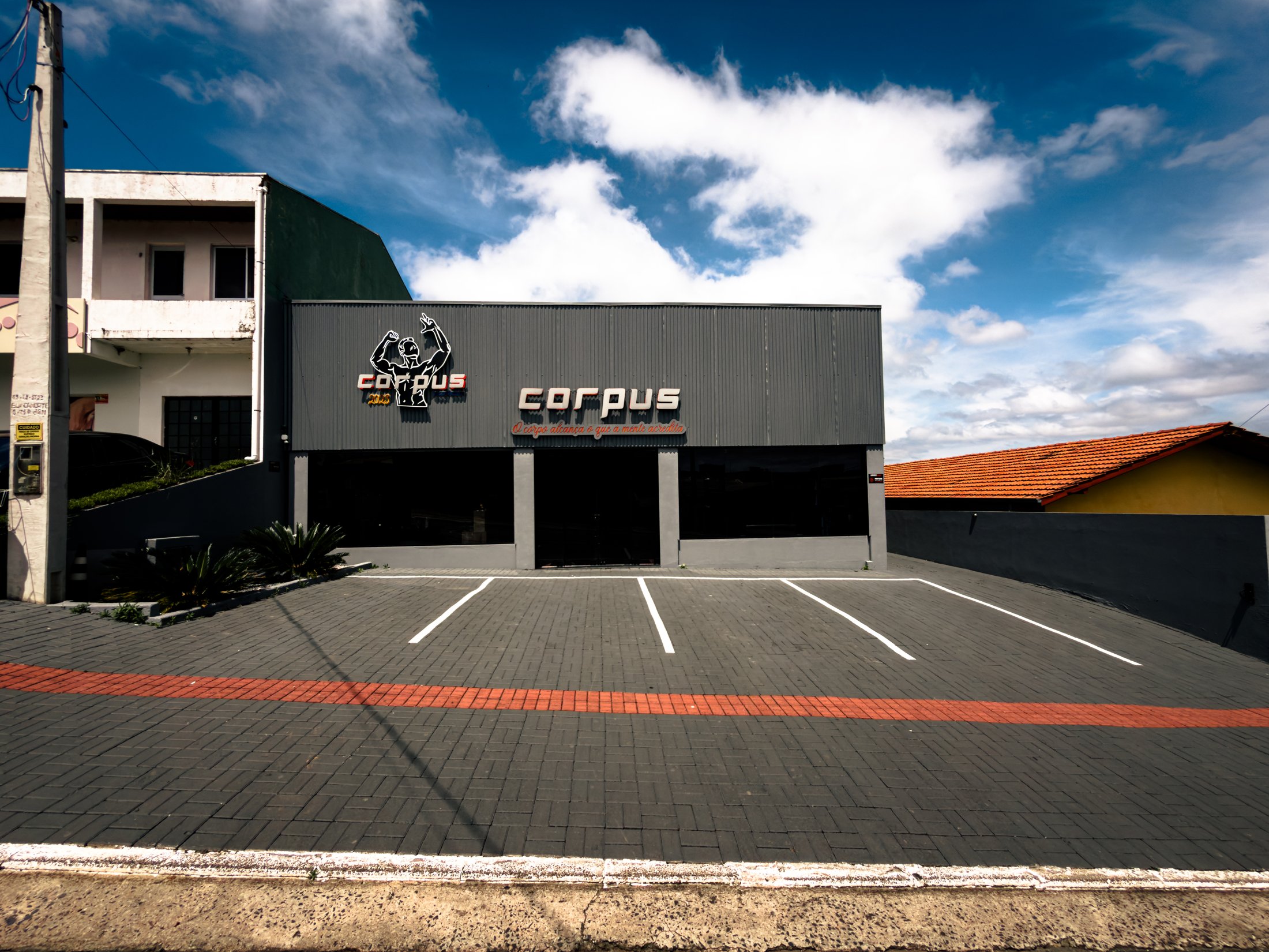 Vista frontal da fachada e do estacionamento da Corpus